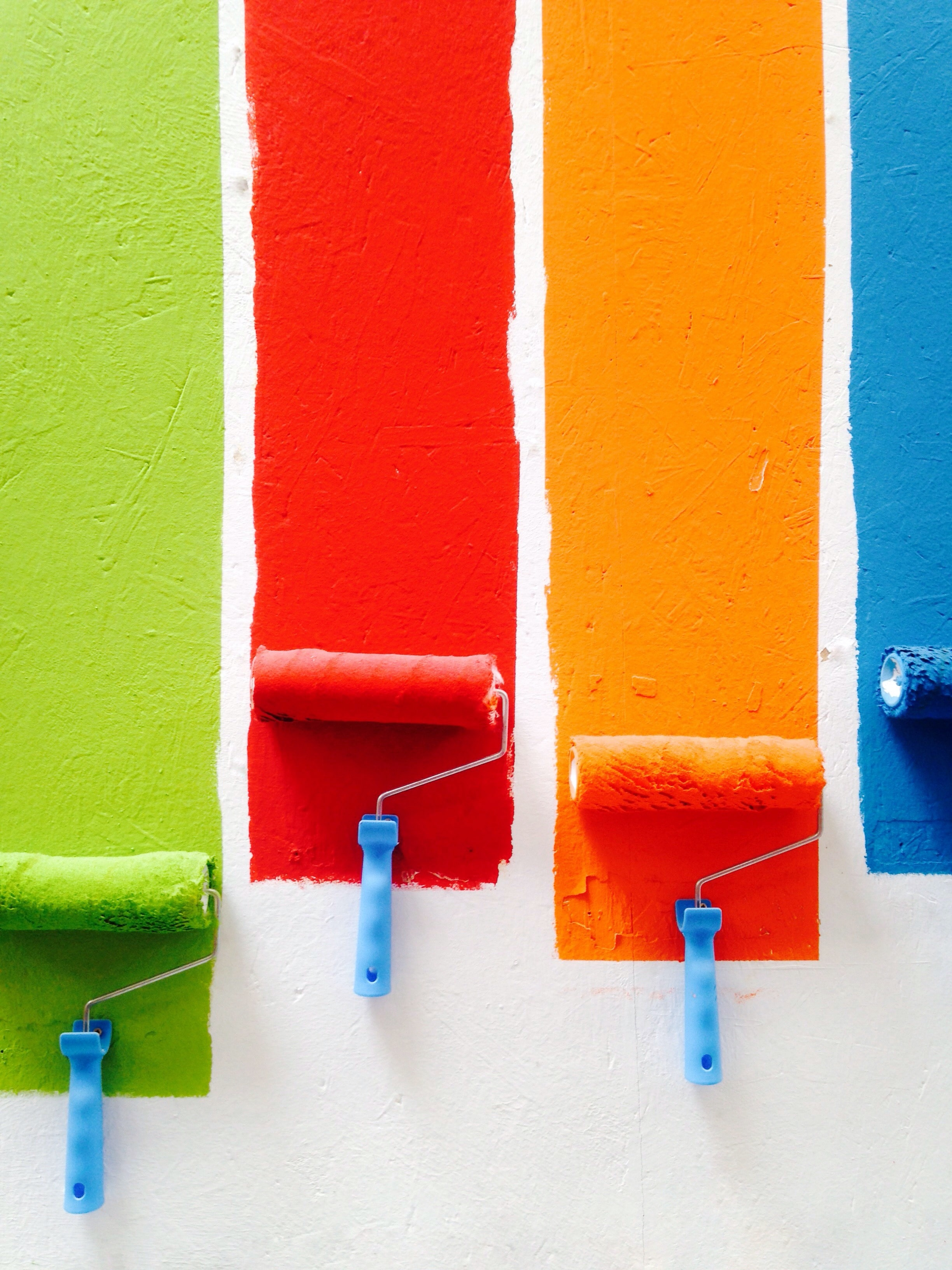 various colors of paint being brushed onto a wall